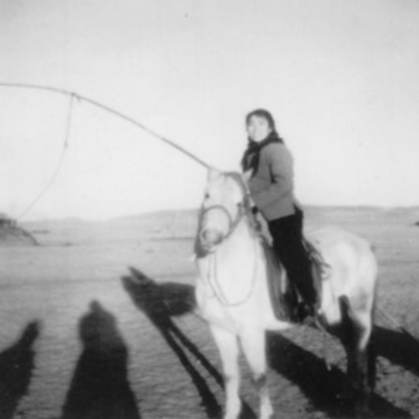 Black and white photo of a young lady on horseback holding a fishing rod